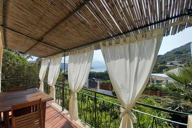 Überdachte Holzterrasse mit Essbereich, Pflanzen und Sitzmöbeln.