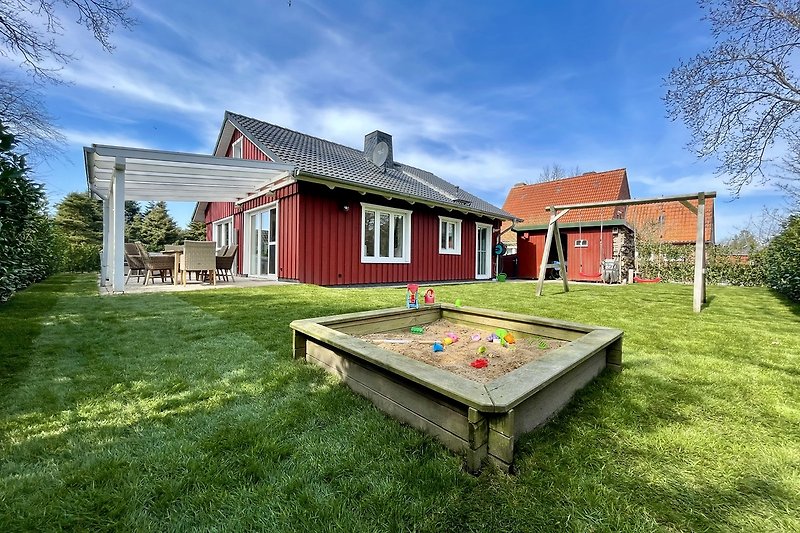 Charmantes Landhaus mit Garten, Bäumen und grüner Wiese.