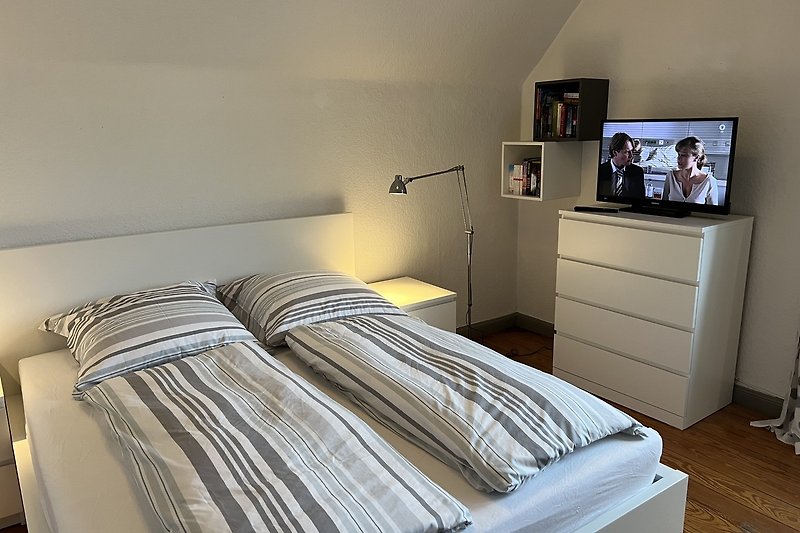 Gemütliches Schlafzimmer mit grauem Holzboden und bequemem Bett.