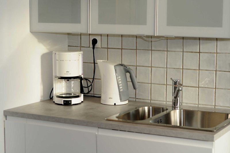 Küchenzeile mit Geschirrspüler, Kaffeemaschine und Wasserkocher