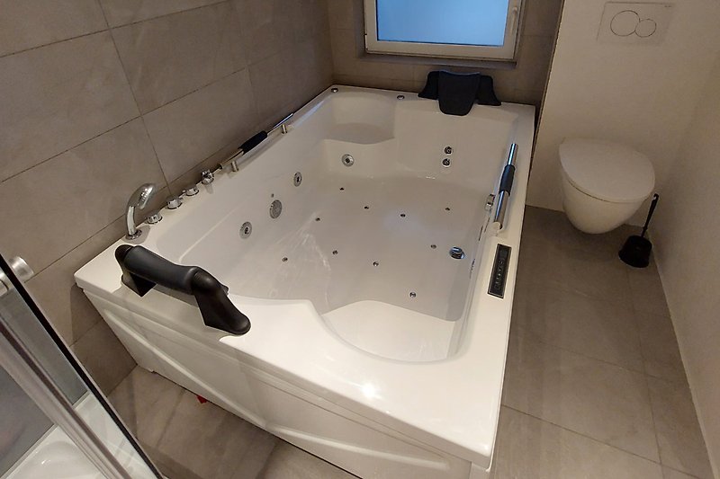 Stilvolles Badezimmer 1 mit Flisenboden und moderner Whirlpool und Dusche