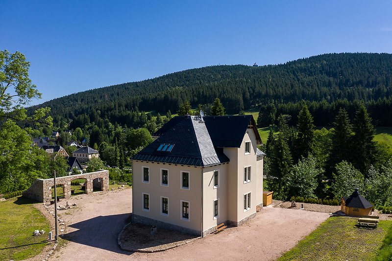 Blick über das Gästehaus mit Freisitz und Kinderspielhaus zum Auersberg