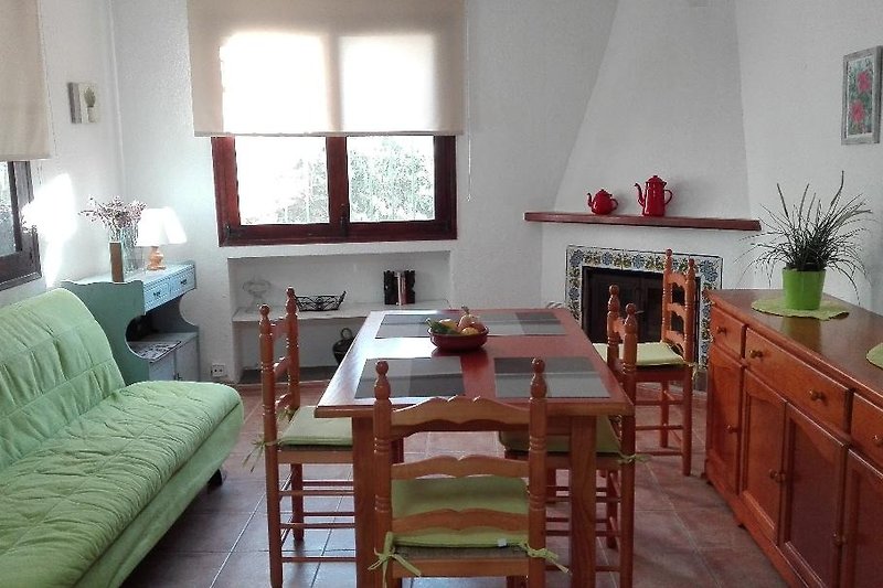 Wohnzimmer mit Holzmöbeln, gemütlicher Sessel und Pflanze.