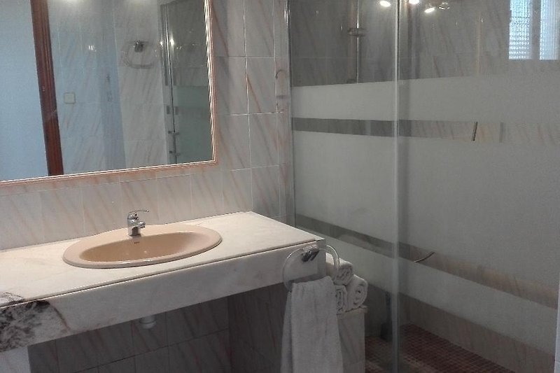 Modernes Badezimmer mit Spiegel, Waschbecken und Glas.