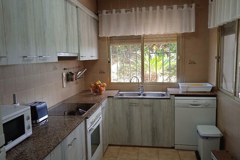 Moderne Küche mit Holzschränken, Fensterfront und Edelstahlspüle.