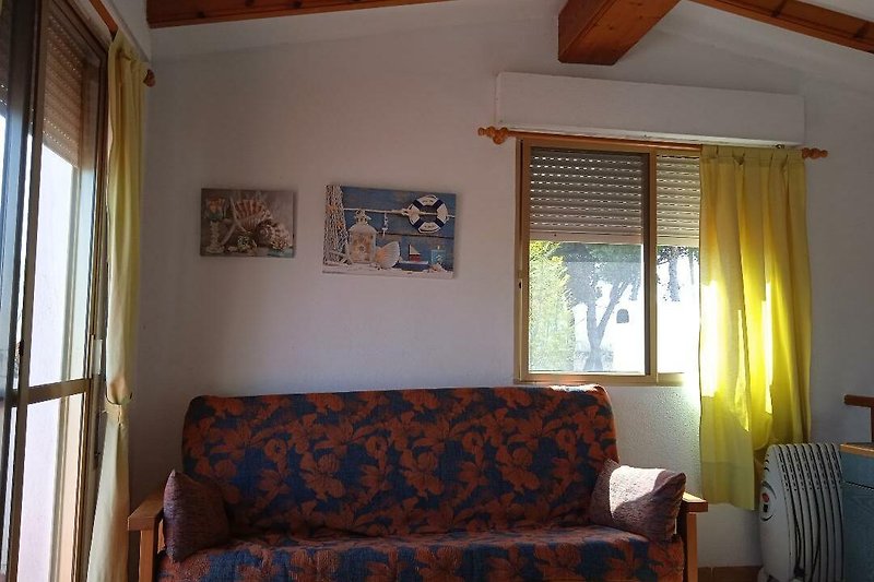 Wohnzimmer mit bequemer Couch, Fenster und Vorhängen.