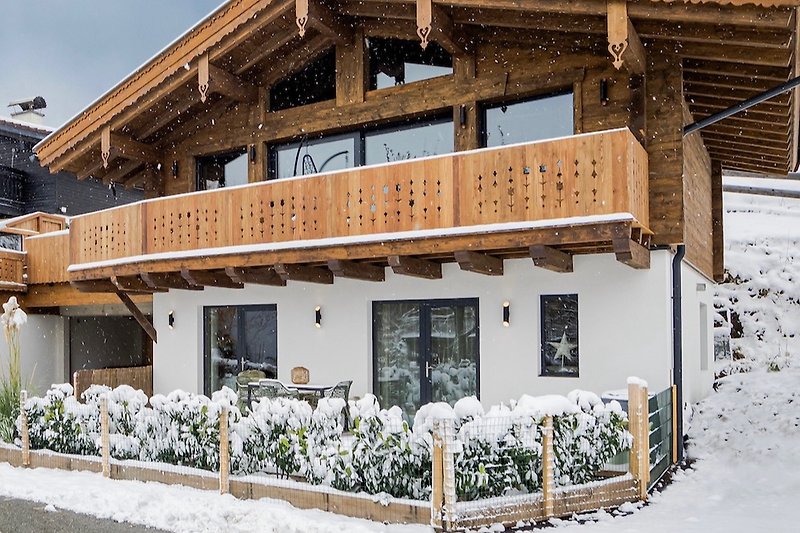 Gemütliches Holzhaus mit winterlicher Landschaft und Balkon.