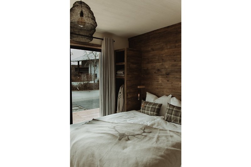 Gemütliches Schlafzimmer mit Holzbett, Lampe und Vorhängen.