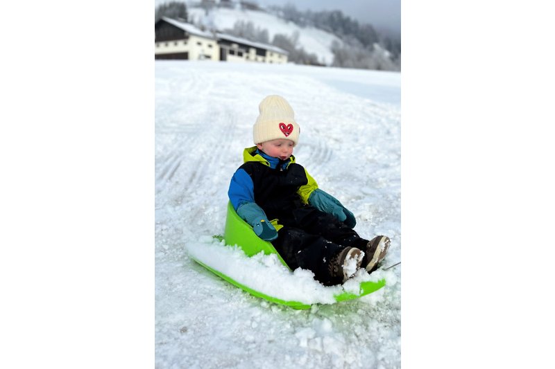 Winterlicher Spaß im Schnee mit Schlitten und Schutzkleidung.