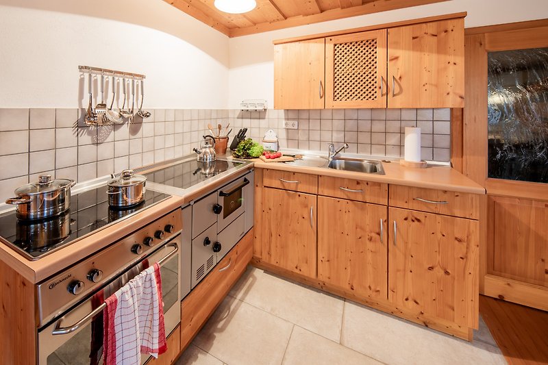 Gemütliche Küche mit Holzmöbeln, Holzofen und modernen Armaturen.