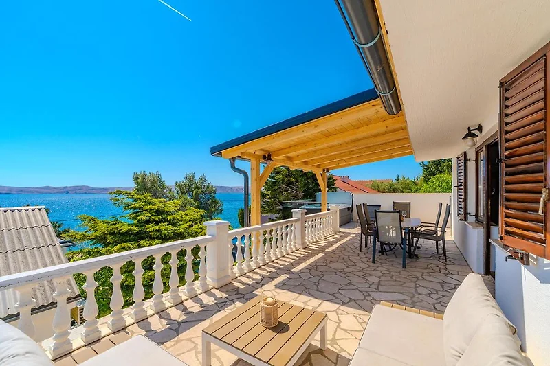 Weitläufige Veranda mit Blick auf Palmen, Bucht und türkisfarbenes Meer.