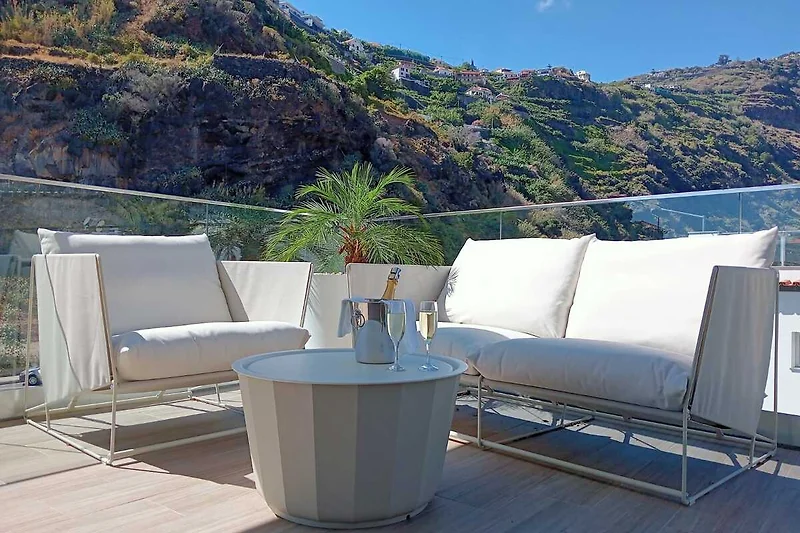 Große Terrasse mit luxuriösen Gartenmöbeln und seitlichem Meer- und Bergblick