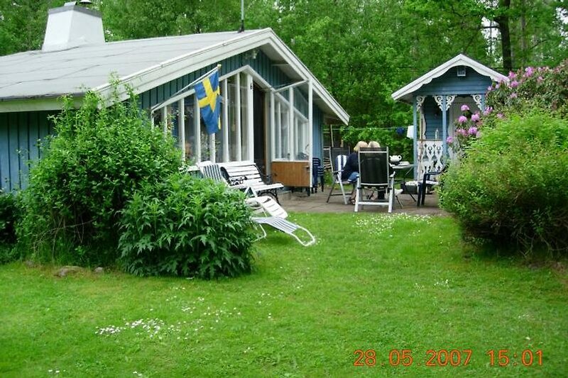 Haus mit einem gepflegten Garten und einer Terrasse mit Gartenmöbel.