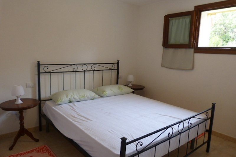 Una camera da letto accogliente con un letto in legno e finestra luminosa.