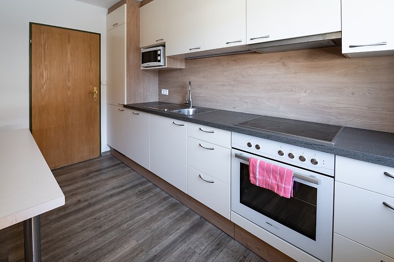 Moderne Küche mit Holzakzenten und Granitarbeitsplatte. Edelstahlgeräte und Gasherd.