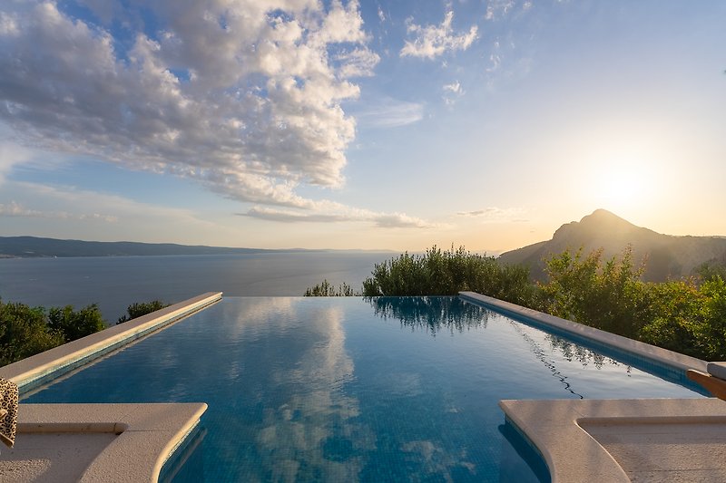 Privater Pool mit Meerblick, umgeben von tropischen Pflanzen.