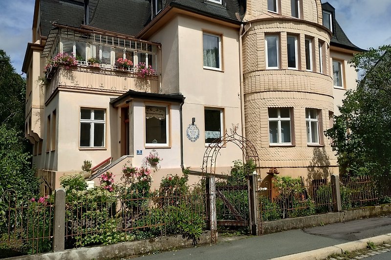 Schönes Haus mit blühenden Pflanzen, Fenstern und einer malerischen Nachbarschaft.