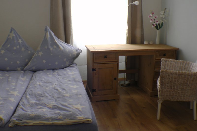 Gemütliches Schlafzimmer mit Holzbett, Nachttischlampe und Vorhängen.