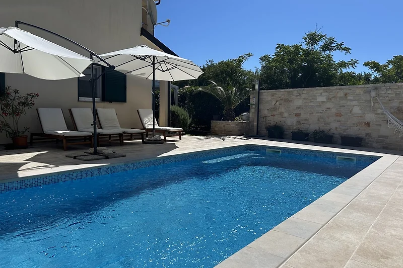 Blick auf den großen beheizten Pool mit schöner Poolterrasse & Sonnenliegen