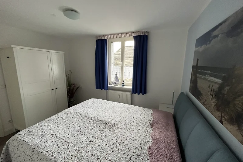 Gemütliches Schlafzimmer mit Holzbett und Fensterdekoration.