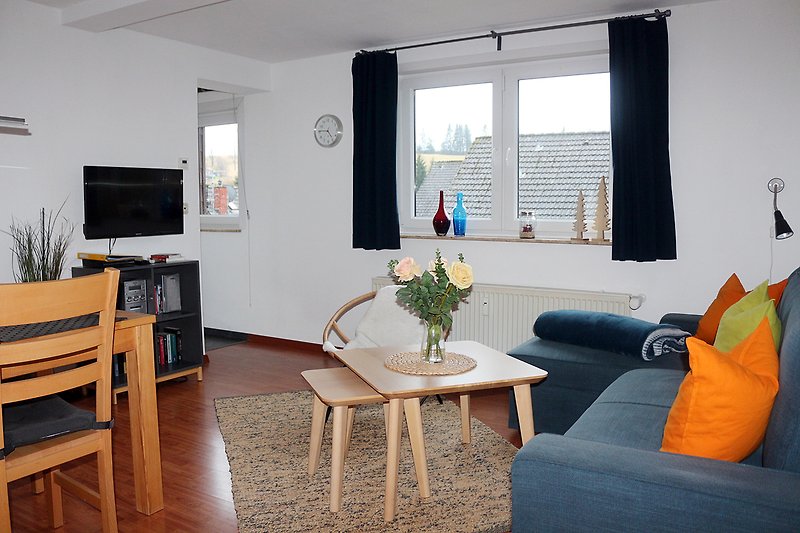 Modernes Wohnzimmer mit bequemer Couch, Holzmöbeln und  Fernseher.