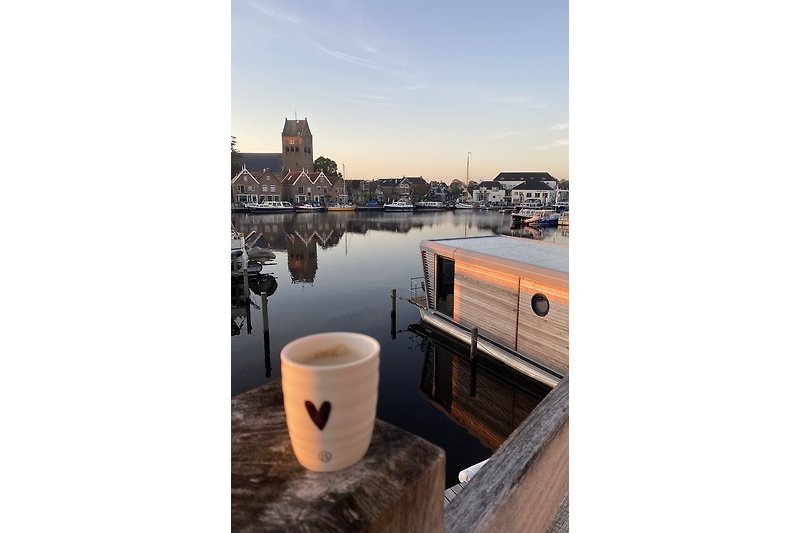 Prachtig uitzicht op het water bij zonsondergang met een houten huis en een boot.