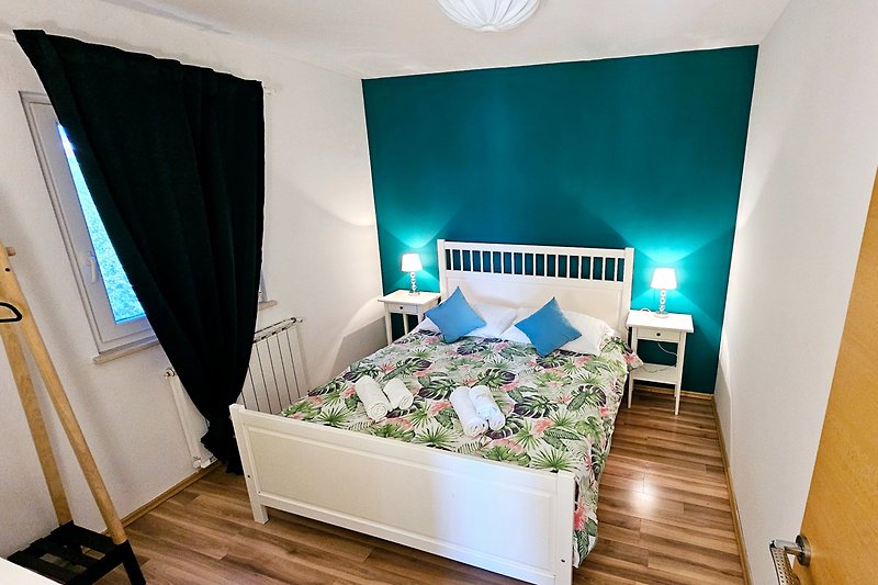 Schlafzimmer mit Holzmöbeln und blauer Bettwäsche.