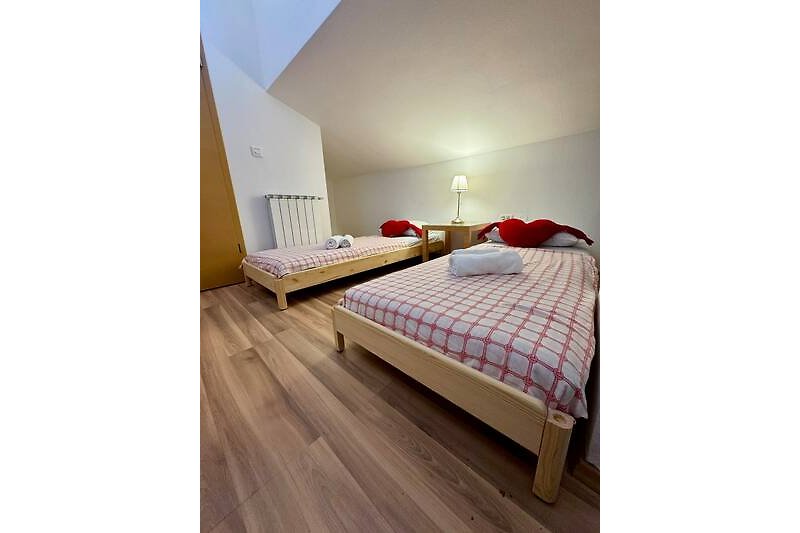 Elegantes Schlafzimmer mit Holzmöbeln, stilvoller Beleuchtung und gemütlicher Bettwäsche.