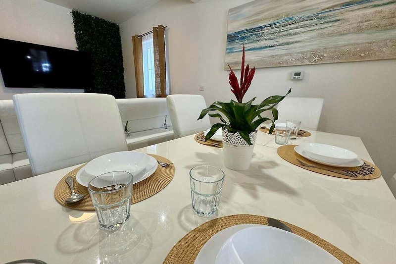 Elegante Tischdekoration mit weißem Geschirr und grüner Pflanze.