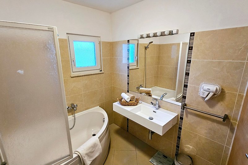 Modernes Badezimmer mit Dusche, Badewanne und Spiegel.