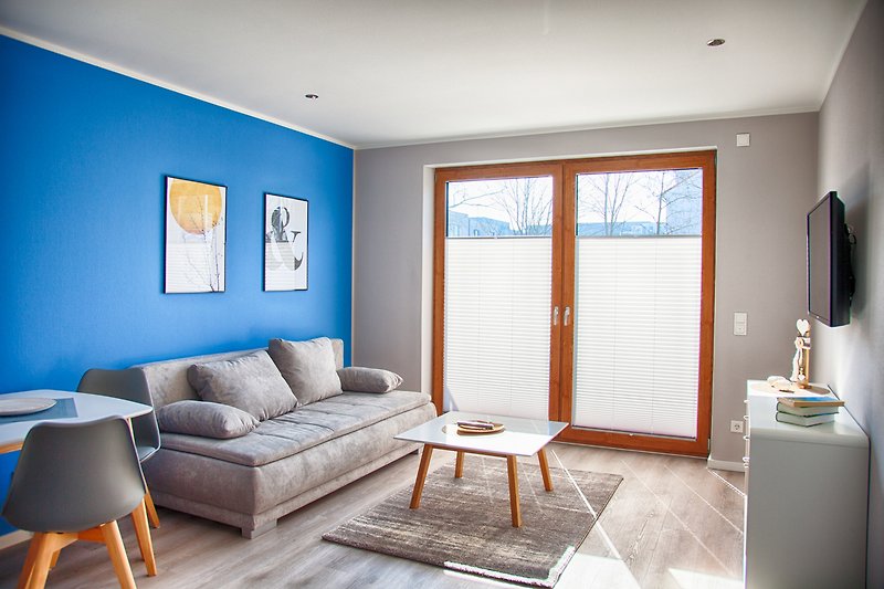 Gemütliches Wohnzimmer mit Holzmöbeln, blauem Sofa und gemütlicher Beleuchtung.