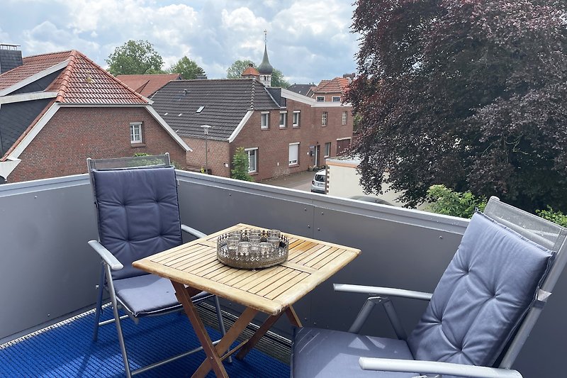 Gemütlicher Südbalkon mit Tisch und  Stühlen mit Blick auf den Glockenturm