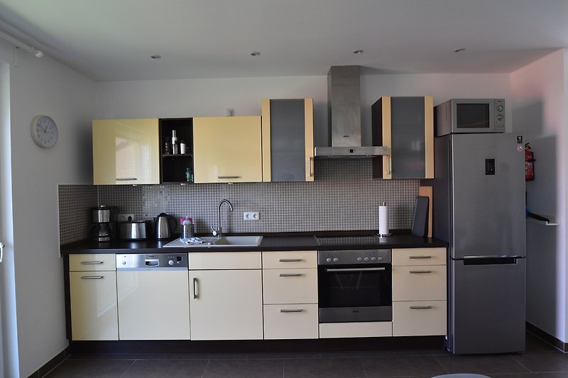 Moderne Küche mit Holzmöbeln, Edelstahl-Spüle und Granitarbeitsplatte.