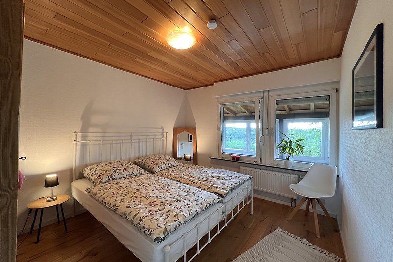 Willkommen in diesem stilvollen Schlafzimmer mit gemütlichem Bett, Holzmöbeln und einer warmen Beleuchtung. Entspannen Sie sich und genießen Sie Ihren Aufenthalt!