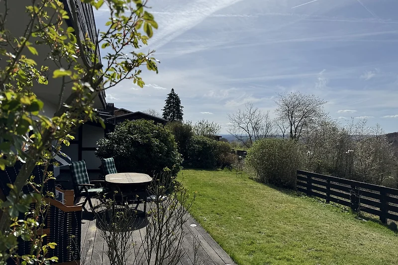 Großer Garten mit Rasen, Koniferen, Outdoor-Möbeln und weitem Himmel.
