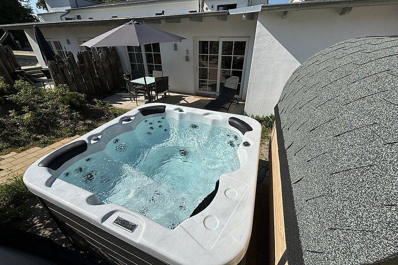 Privater Pool mit Jacuzzi und Pflanzen im sonnigen Garten.