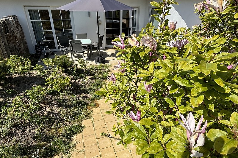 Charmanter Garten mit blühenden Pflanzen und gepflegtem Rasen.