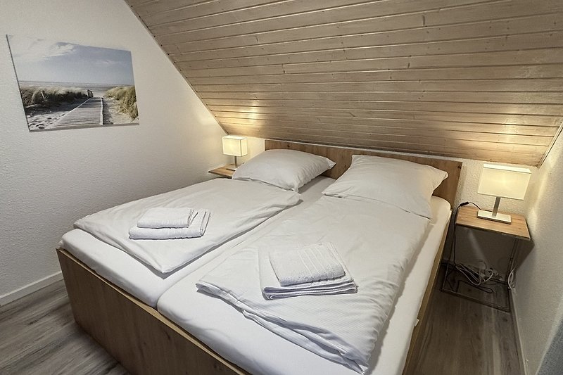 Schlafzimmer mit bequemem Bett, Holzmöbeln und gemütlicher Beleuchtung.