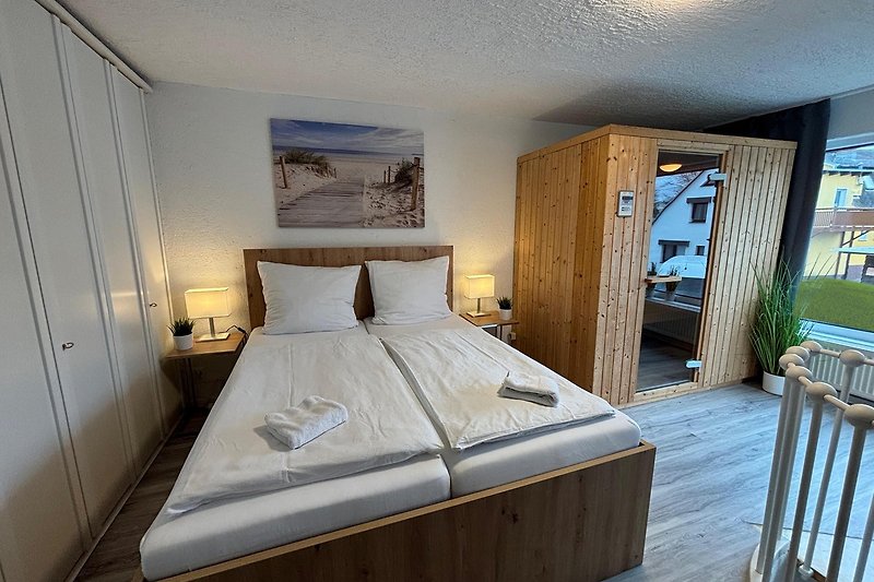 Schlafzimmer mit elegantem Holzbett, Lampen, Pflanzen & Bettwäsche.