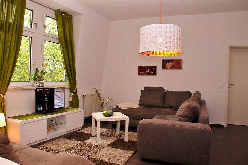 Willkommen in diesem stilvoll eingerichteten Wohnzimmer mit bequemer Couch, Pflanzen und gemütlicher Atmosphäre. Entspannen Sie sich und genießen Sie den Komfort!