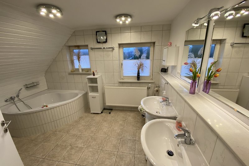 Badezimmer mit Badewanne, Spiegel und 2  Waschbecken.