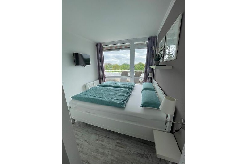 Gemütliches Schlafzimmer mit stilvollem Bettgestell, Fenster und gemütlichen Kissen.
