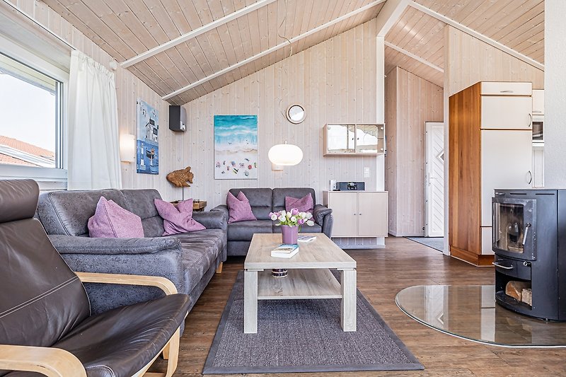 Gemütliches Wohnzimmer mit lila Dekoration, Holzboden und moderner Einrichtung.