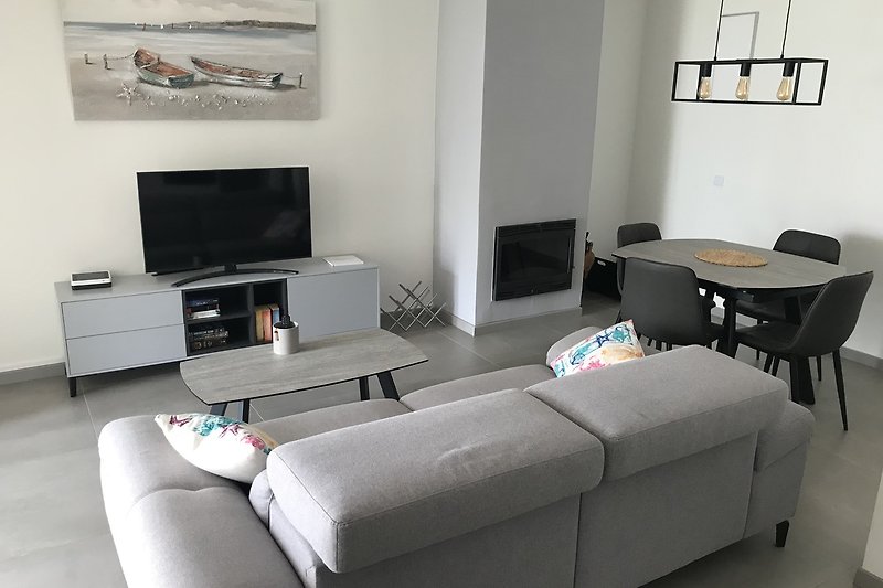 Modernes Wohnzimmer mit bequemer Couch, TV, stilvollem Interieur und Lampen. Gemütliche Atmosphäre.