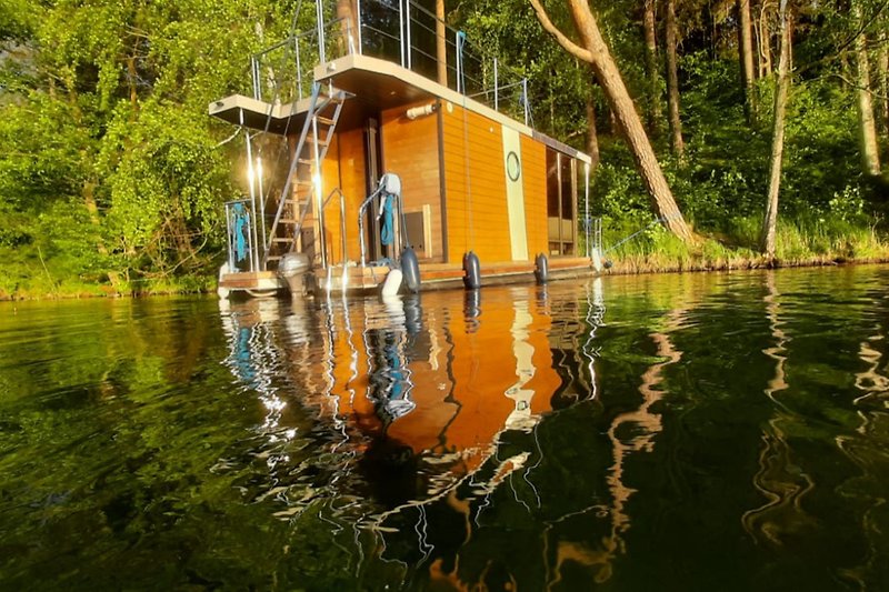 Ein malerisches Hausboot am Seeufer mit üppiger Vegetation.
