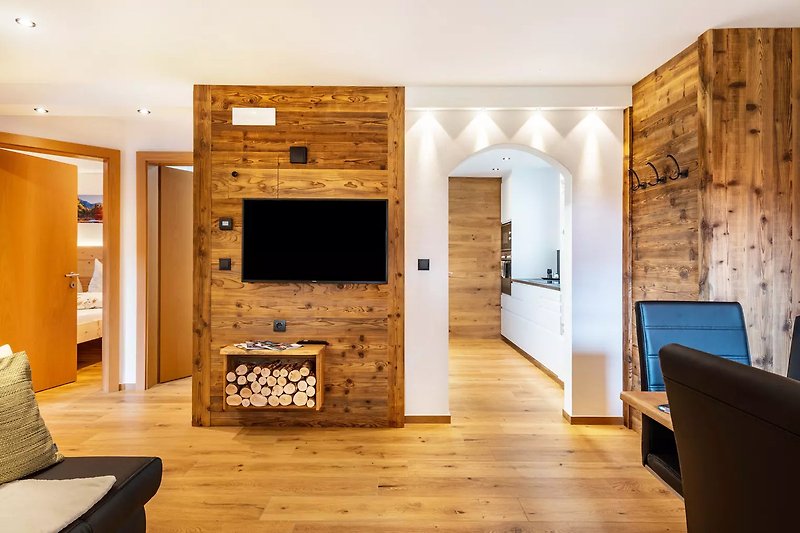 Gemütliches Wohnzimmer mit Holzmöbeln, Kamin und Fernseher.