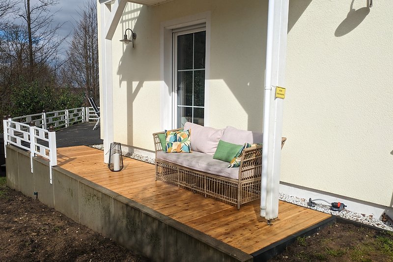 Sonnige Holzterrasse mit Outdoor Couch