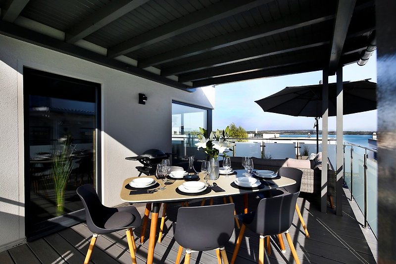 Balkon mit Esstisch und Lounge Sofa / Blick auf den See