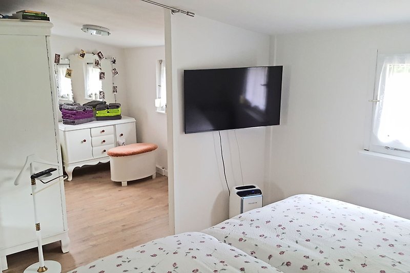 Schlafzimmer mit erhöhten Betten, Fernseher und Ankleidezimmer mit "Künstlergarderobe"