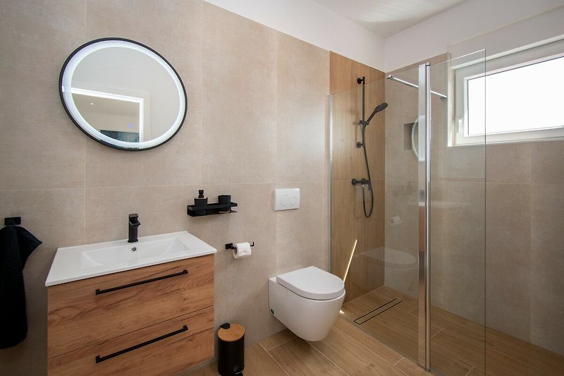 Modernes Badezimmer mit elegantem Spiegel, Armatur und Holzmöbeln. Ideal für Entspannung!